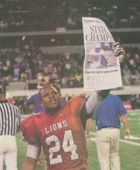 A Henderson football player holds up a newspaper that heads "State Champs" in Fourth Down, Forever to Go